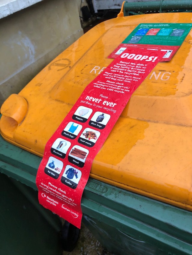 A recycling bin with a sticker advising that the bin contains non-recyclable material